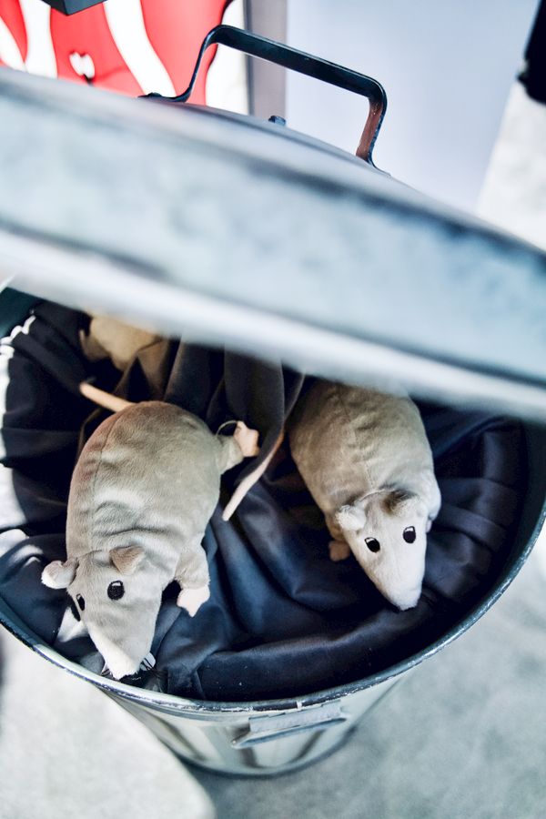 Plush rats peek out from the trash can stationed at the Thank Goodness You're Here! section of the 2023 PAX West booth